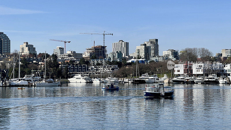 3月一个阳光明媚的日子，温哥华格兰维尔岛的港口，有许多船只和露台