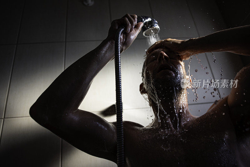 肌肉男洗头和身体，站在浴室的水下面