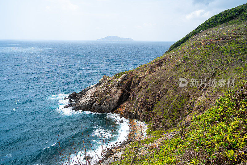 海浪拍打着海滩上的岩石，海水随着阳光飞溅到天空。一个宁静的越南孔岛，是越南海岛的天堂