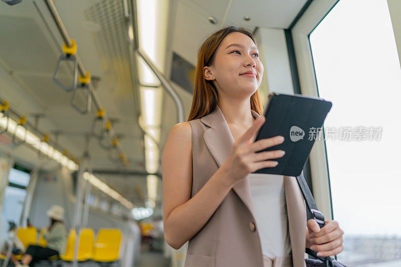 都市旅行生活方式。联网通勤者。亚洲女商人带着数码平板电脑乘坐单轨列车