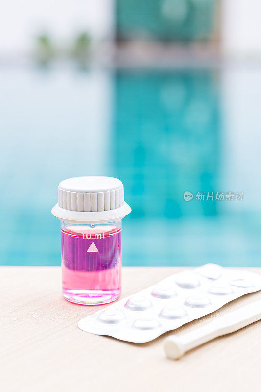 游泳池池水装在玻璃小瓶中，并配有pH表试剂和泳池边的搅拌棒