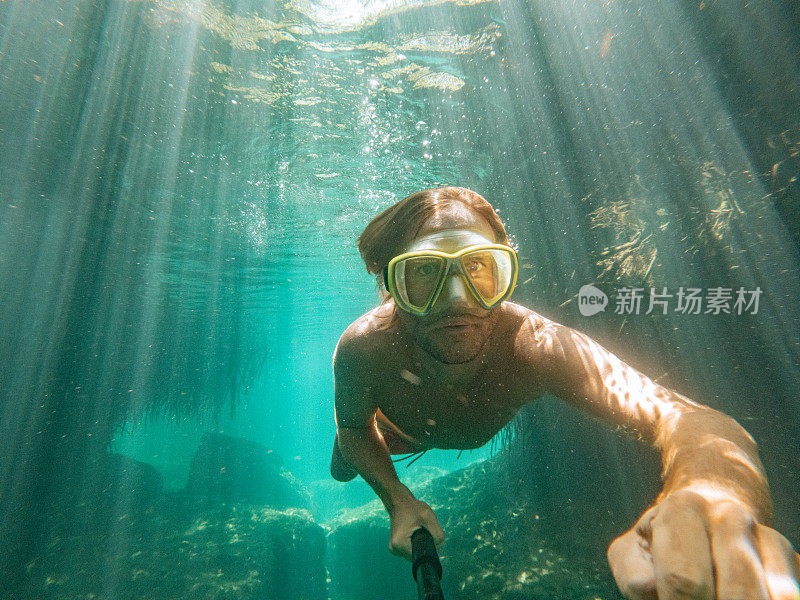 男子在清澈的水中游泳时在水下自拍