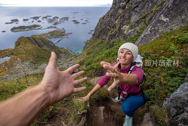 徒步旅行者帮助队友到达山顶