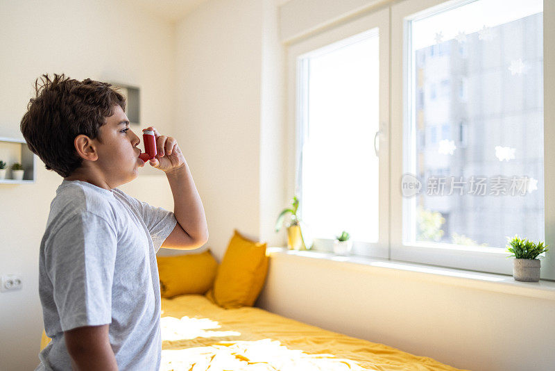 白人男孩使用哮喘吸入器的侧面图