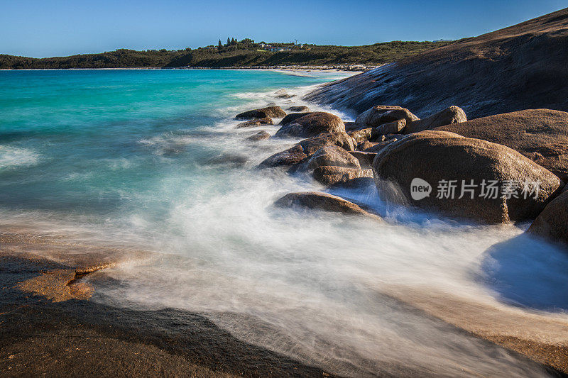 慢快门海岸场景，海水蓝色的海浪轻轻地冲刷着岩石