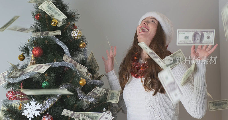 钱雨，一位戴着圣诞老人帽子的年轻女子站在圣诞树旁，钱正从树顶落下。除夕之夜，美梦成真。
