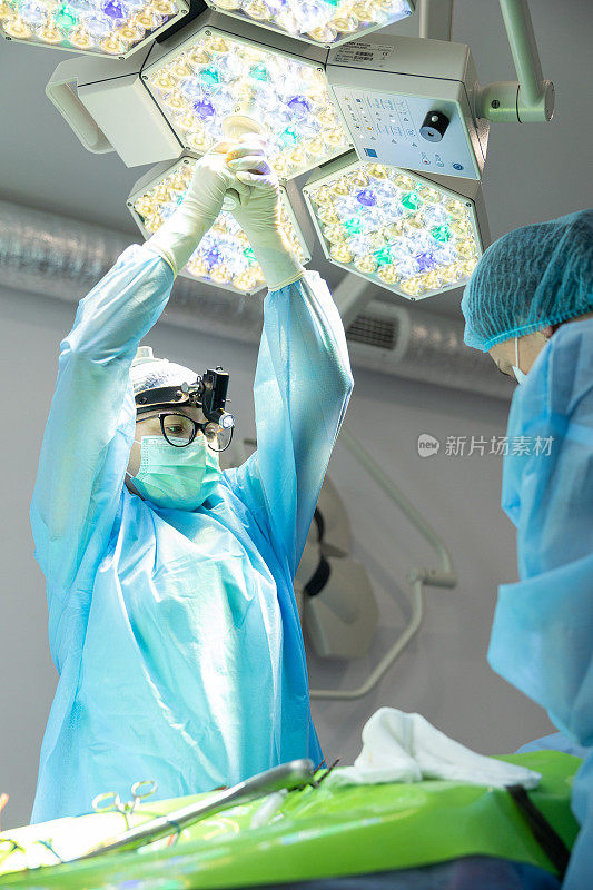 整形外科医生调整手术灯进行手术。