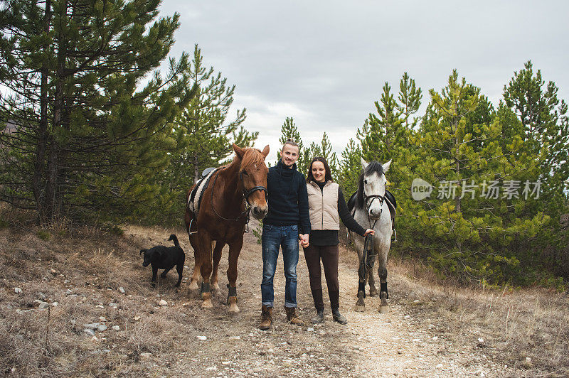 年轻夫妇遛着马和狗