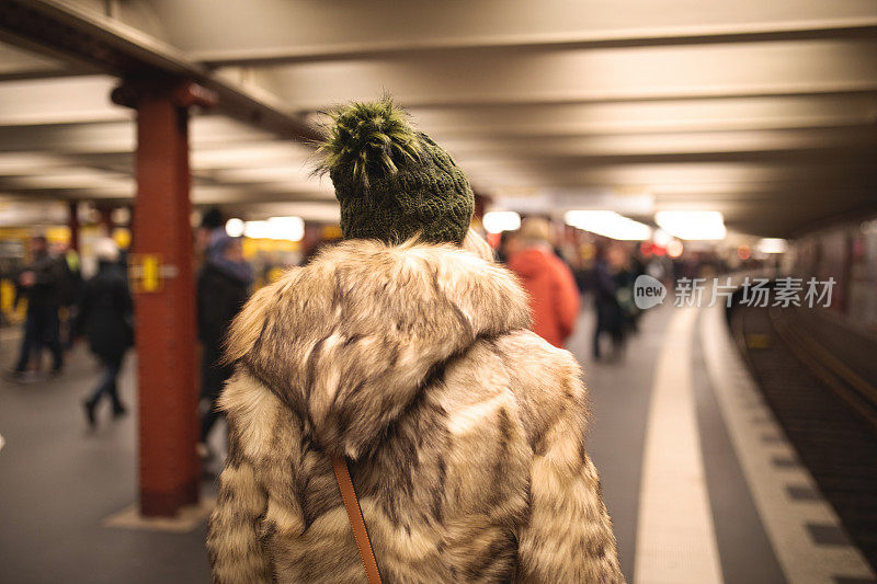 一个金发女孩独自走过地铁站的后视图