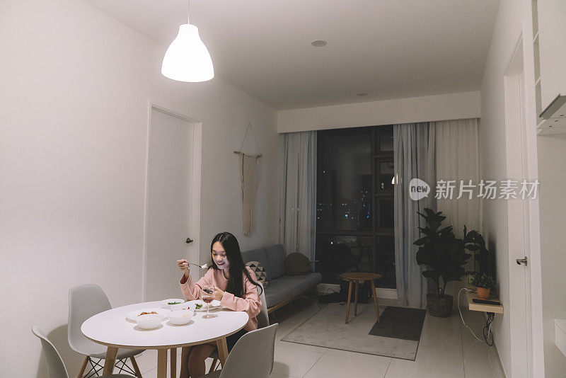 亚洲华人女性在家吃饭用手机独自