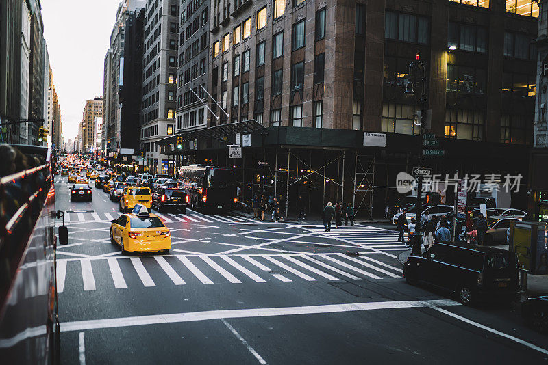 市中心大道上的交通拥堵，黄色出租车和汽车在堵塞，曼哈顿的建筑在纽约大道上，很多交通工具在晚上开车，环境影响减少