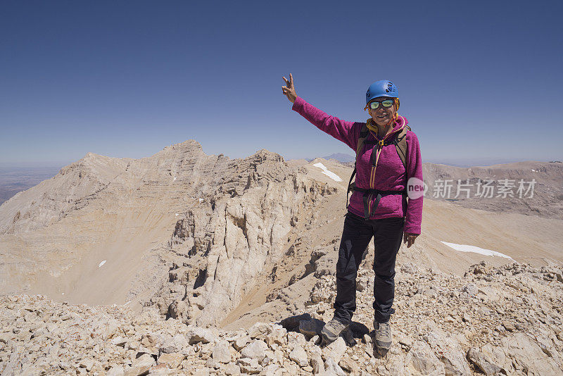 一位女登山者正在山顶做和平手势