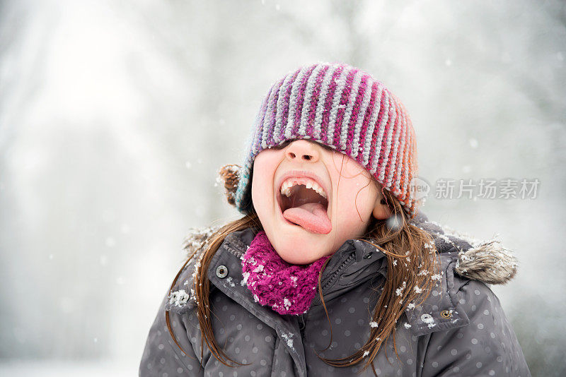 小女孩在雪中玩耍，她试图用她的嘴去接雪花