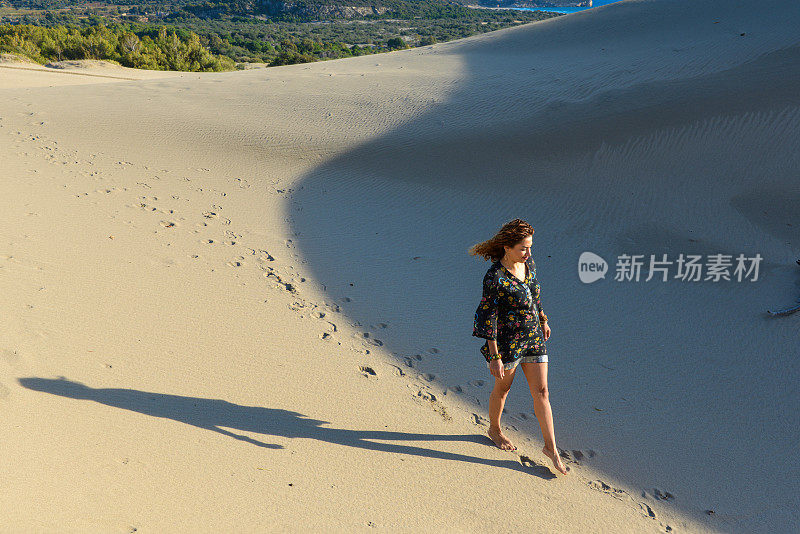 一个年轻漂亮的女人走在沙丘上。