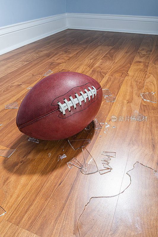 一个美式足球，地板上有破碎的玻璃