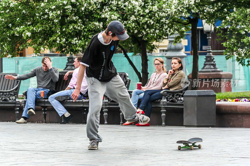 一个学生在大剧院前的广场上玩滑板。