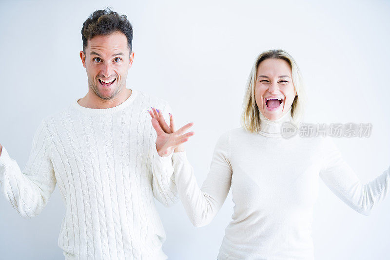 年轻美丽的夫妇穿着休闲t恤站在孤立的白色背景庆祝疯狂和惊讶的成功，举起手臂，睁开眼睛兴奋地尖叫。赢家的概念