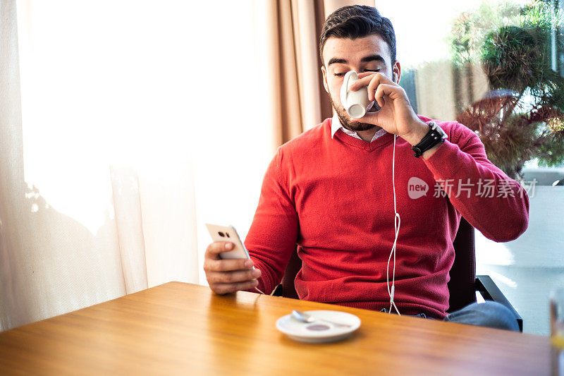 男人坐在café喝咖啡和使用手机