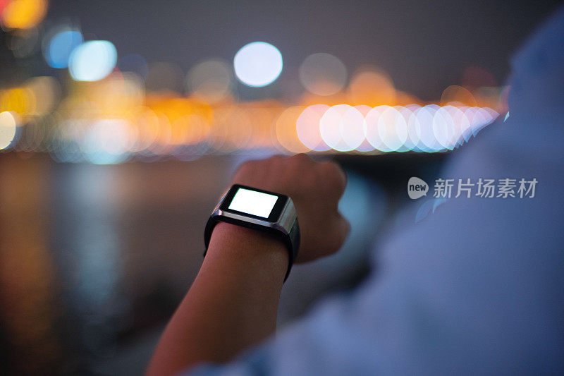 年轻的亚洲人晚上戴着智能手表