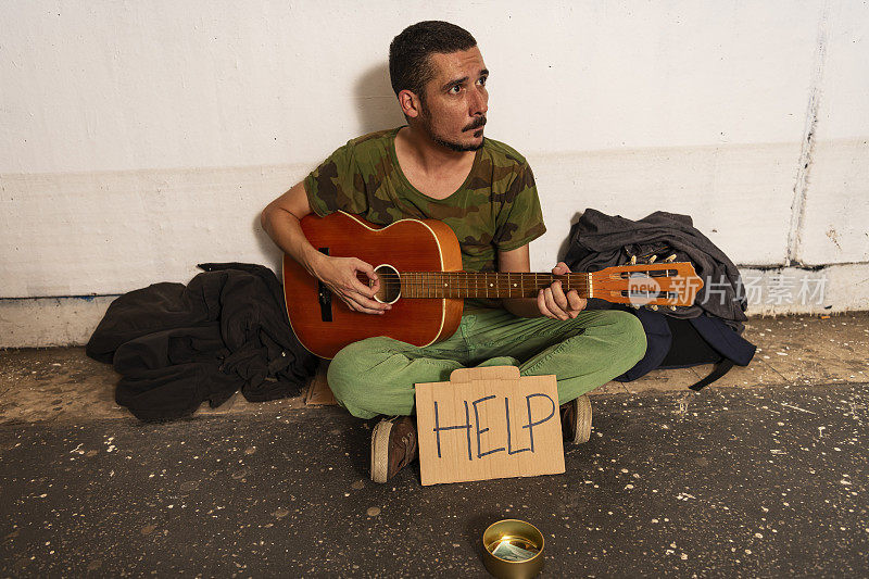 无助的乞丐在街上弹吉他