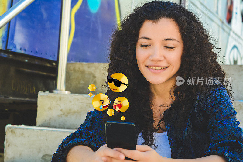 用智能手机发送表情符号的女人。