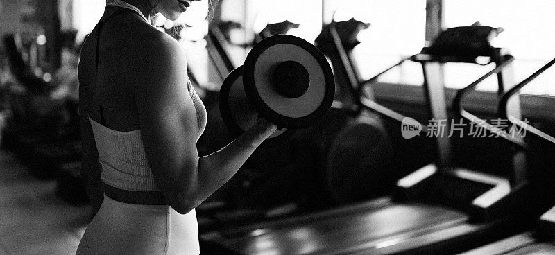 一个不知名的运动女性在健身俱乐部拿着哑铃锻炼