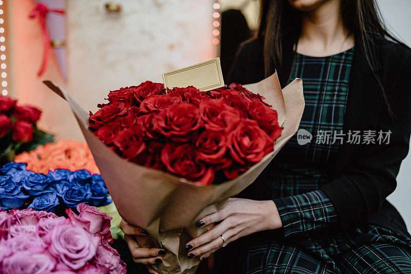 花商拿着红玫瑰花束在店里