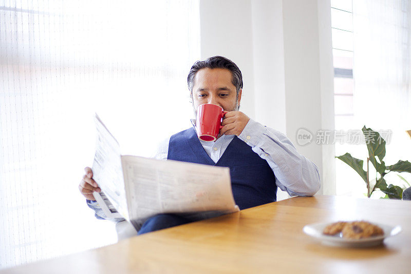 男人在家里喝茶看报纸