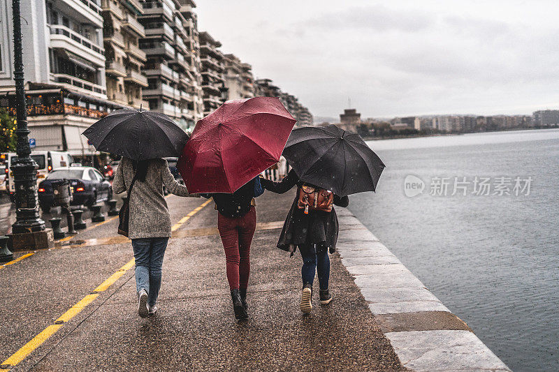 女性朋友在雨天撑着雨伞散步