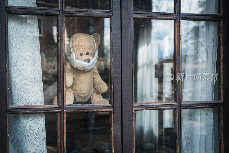 带着医用口罩的泰迪熊向窗外望去