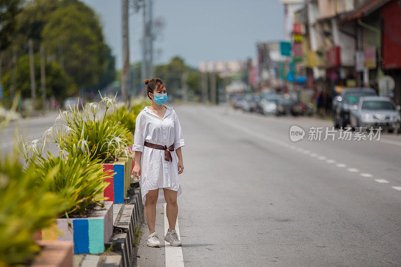 亚洲妇女戴面罩以预防流感病毒外出购物。新冠肺炎封锁期间，街上空荡荡的人。