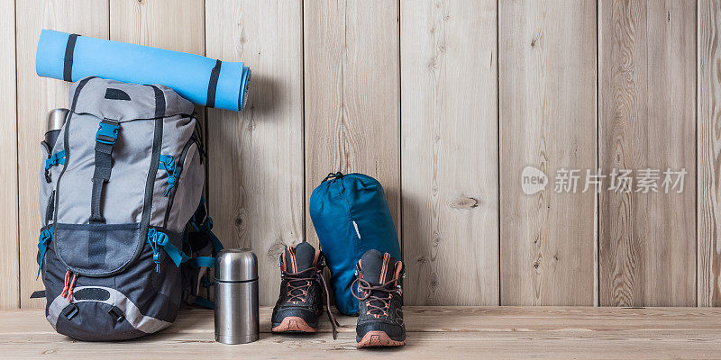 露营装备，鞋子，背包和一个保温瓶，木质背景