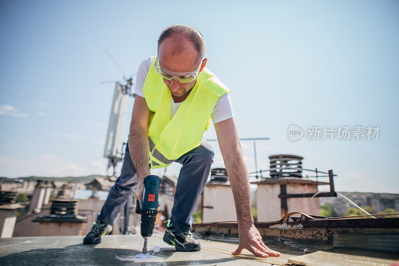 成熟的屋顶师傅与电动螺丝刀