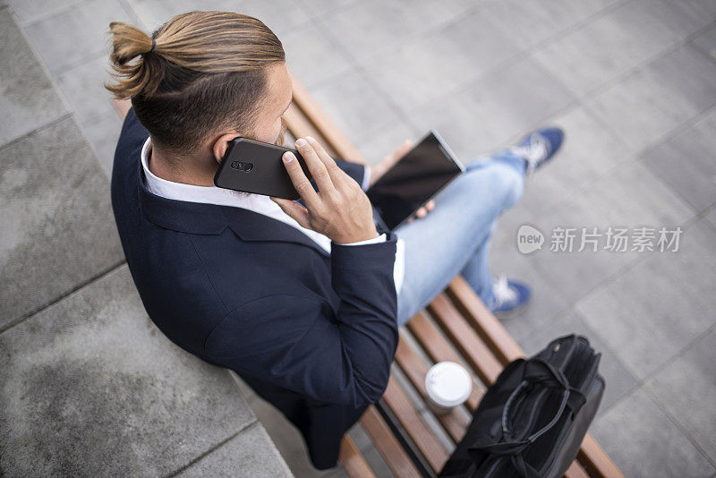 年轻的潮人商人在城市里用触控板上网，库存照片