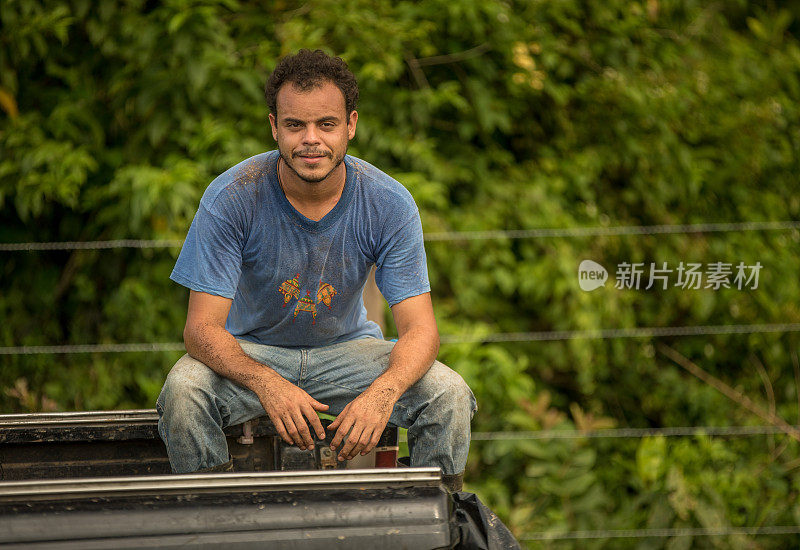 描绘一个年轻人坐在种植园的卡车后面