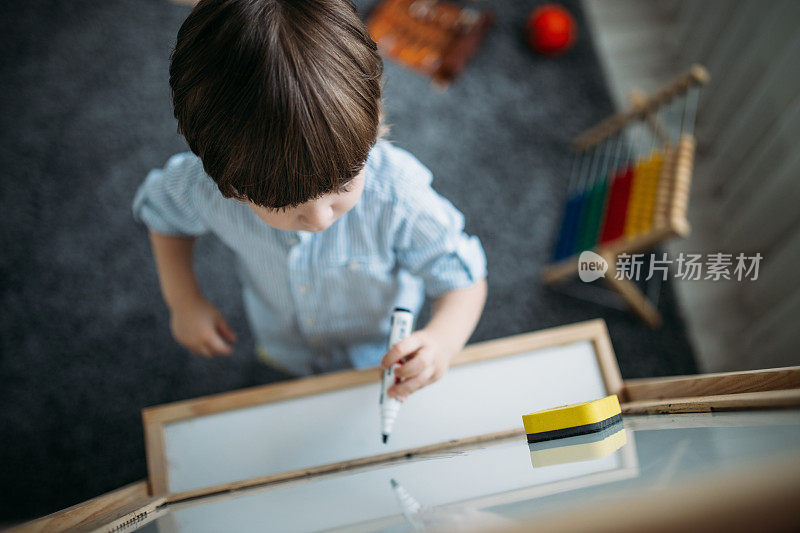 蹒跚学步的小男孩在白板上画画