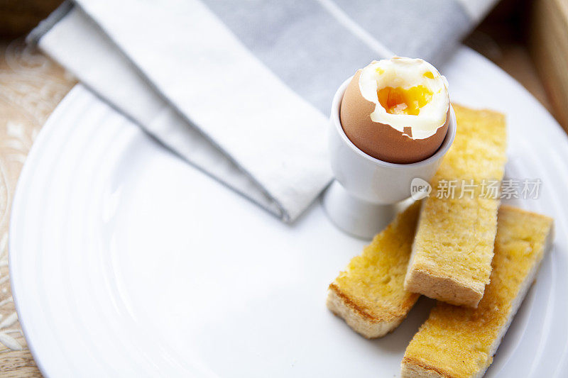 半熟的煮鸡蛋和士兵在一个白色的盘子里有拷贝空间