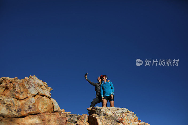 两个女性朋友站在一块岩石上自拍