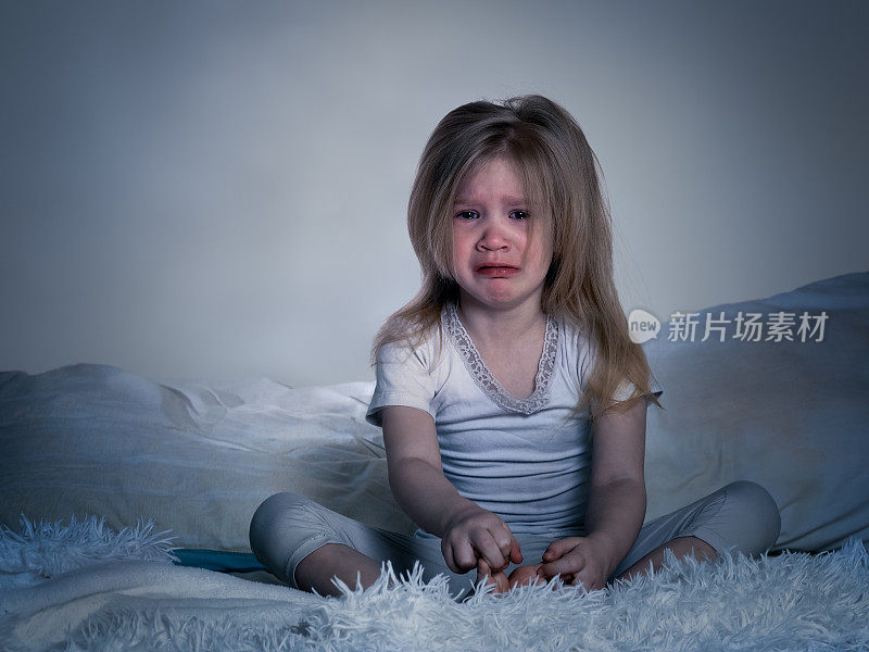 婴儿在哭。一个小女孩在床上过夜