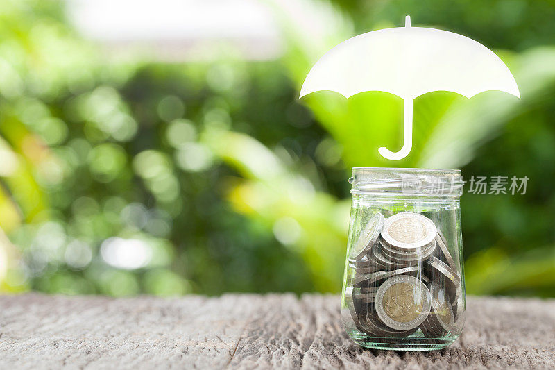承保范围，保险或保护概念，硬币在玻璃，伞的自然背景。