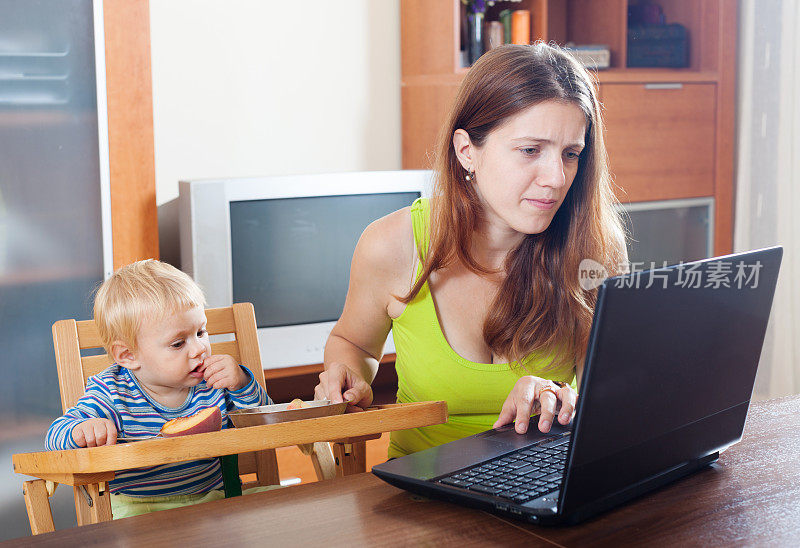 年轻女人用笔记本电脑和婴儿工作