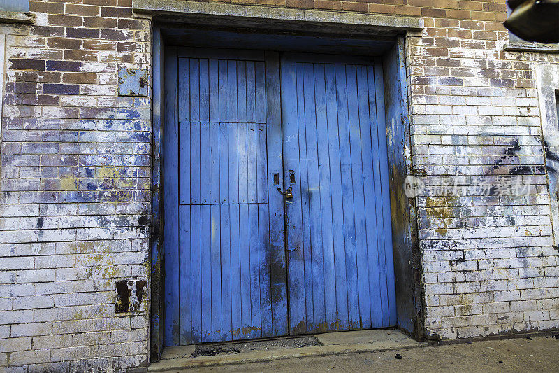 一扇旧的蓝色门，墙上是垃圾