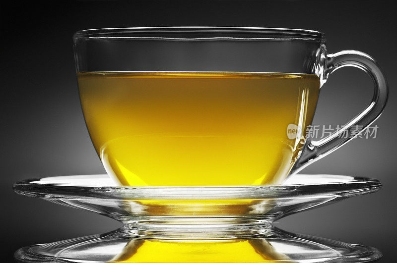 草本茶在玻璃杯和茶碟在黑色的背景