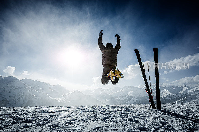 快乐的高山滑雪者在顶部的空中跳跃