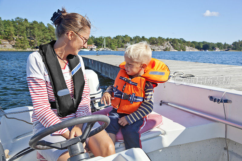 母亲和儿子穿着救生衣在一艘小船上