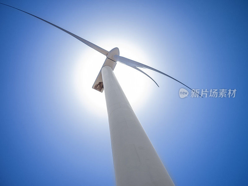 白色风力涡轮机与太阳在背景