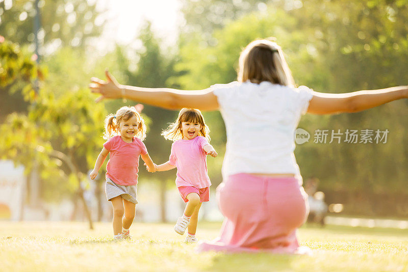 两个穿粉色衣服的小女孩跑向她们的妈妈