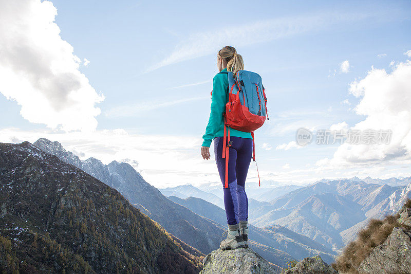 年轻女子徒步到达山顶，沉思风景