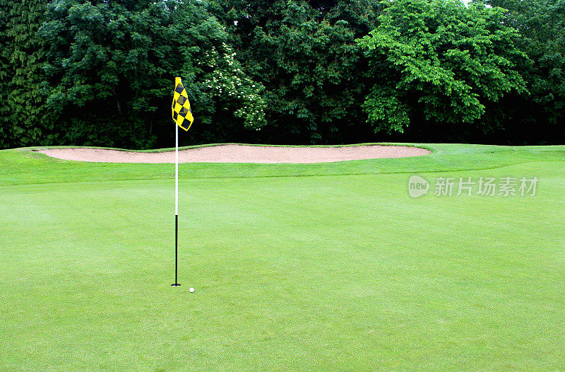 在高尔夫球场的洞内铺上绿草和旗子