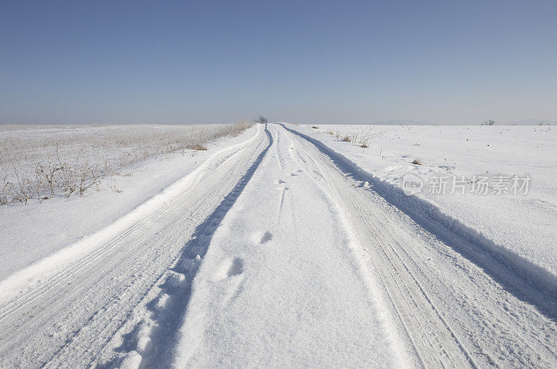 冬天穿过白雪覆盖的田野的土路